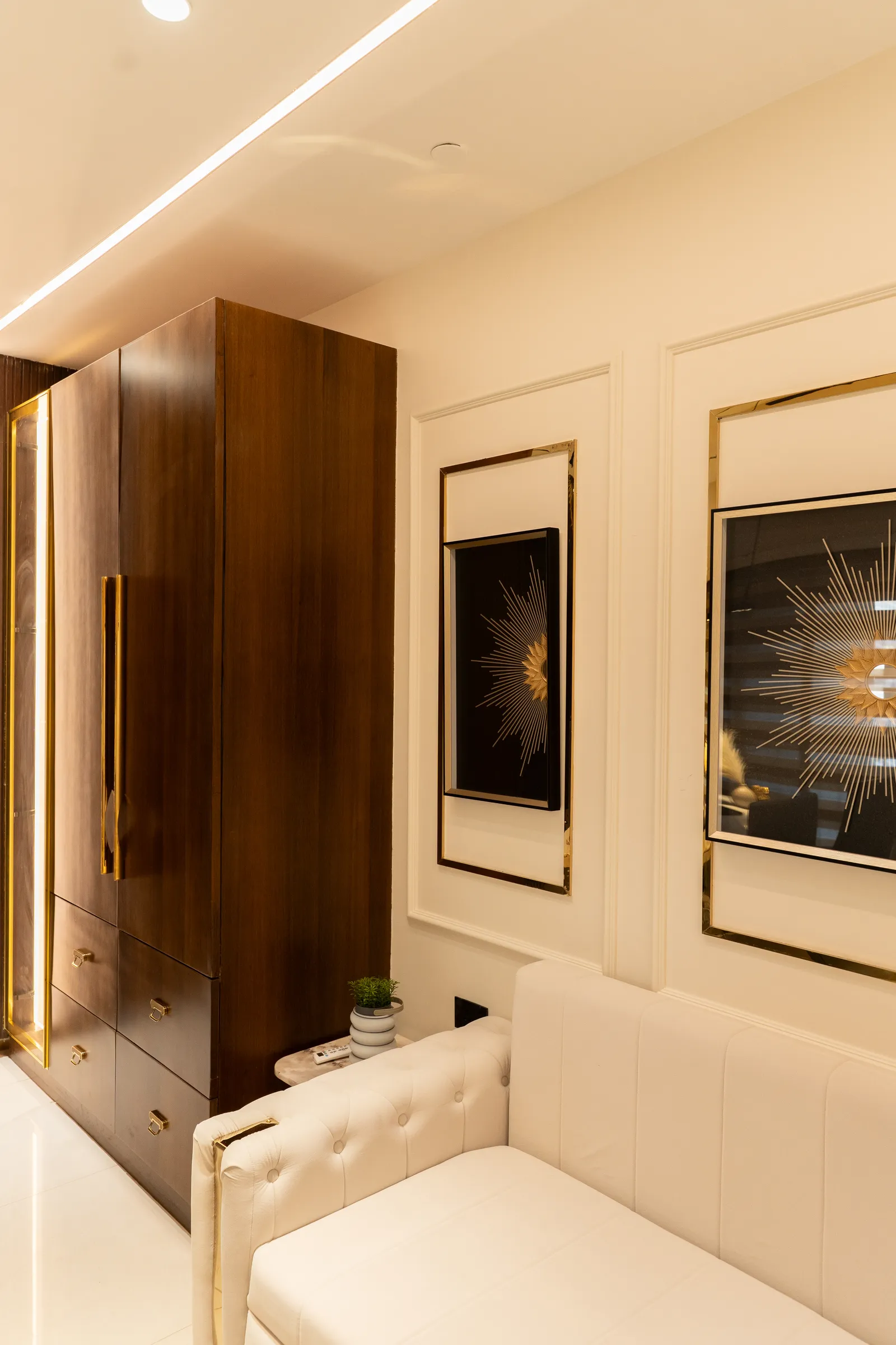 Walnut wardrobe beside framed artwork in the lounge — Abhishek's Residence